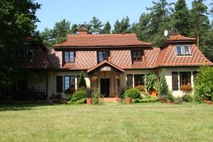 a house with a tiled roof on a yard at Lisi Dwór in Czarny Młyn