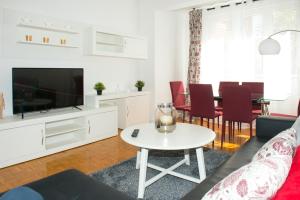 ein Wohnzimmer mit einem Sofa, einem TV und einem Tisch in der Unterkunft Parque del Carmen in Logroño
