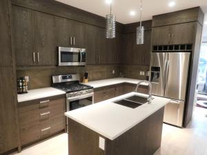 una cocina con armarios de madera y electrodomésticos de acero inoxidable en 3 Bedroom House #37, Sunalta Downtown en Calgary