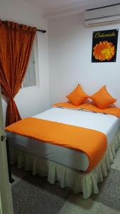 um quarto com uma cama com almofadas laranja e uma janela em Casa Villavicencio em Villavicencio