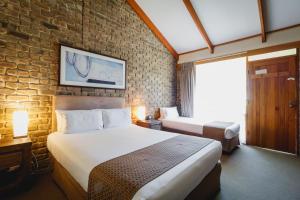 ein Schlafzimmer mit einem großen Bett und einer Ziegelwand in der Unterkunft The Lodge in Hahndorf