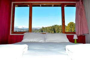 1 dormitorio con 1 cama blanca grande y ventana en Casa Las Moras en San Martín de los Andes