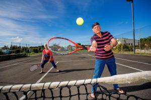 a man holding a tennis racquet on a tennis court at BIG4 NRMA Warrnambool Riverside Holiday Park in Warrnambool