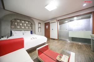 une chambre avec un grand lit et une chaise rouge dans l'établissement Firenze Motel, à Asan