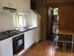 a kitchen with white cabinets and a stove top oven at A'Wangralea Caravan Park in Mallacoota