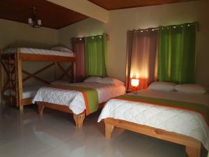 Mountain Faro Hotel في مونتيفيردي كوستاريكا: سريرين بطابقين في غرفة مع ستائر خضراء