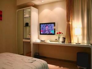 a hotel room with a television on a desk with a bed at Tomolo Hotel Wuzhan Branch in Wuhan