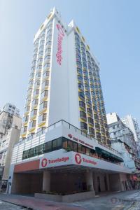 een hoog gebouw met een bord erop bij Travelodge Kowloon in Hong Kong
