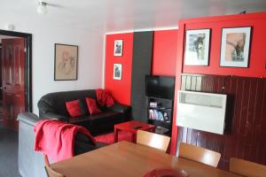 a living room with red walls and a black couch at Avoca Park Equestrian Farmstay in Macclesfield