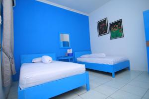 a blue room with two beds in it at Hotel Boegenviel Syariah in Lamongan +9 photos