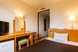 una camera d'albergo con letto e TV di Komagane Premont Hotel a Komagane