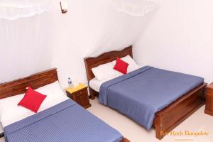 two beds with red pillows in a room at kin Rock Bungalow in Hatton