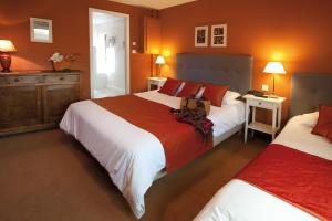 two beds in a bedroom with orange walls at Le Gouverneur Hotel in Obernai