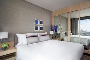 a bedroom with a large white bed and a window at Avani Plus Riverside Bangkok Hotel in Bangkok