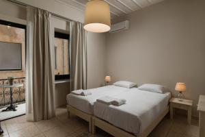 a hotel room with a bed, lamps and a television at Nonnalena Boutique Hotel in Chania