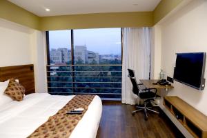 a hotel room with a bed and a desk with a computer at Hotel Mumbai House Andheri East, Mumbai in Mumbai
