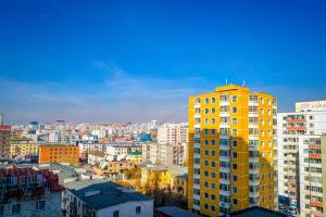 ein hohes gelbes Gebäude in einer Stadt mit Gebäuden in der Unterkunft Zaya Hostel in Ulaanbaatar