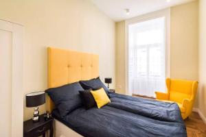 ブダペストにあるVentura régiのベッドルーム(大きな青いベッド1台、黄色い椅子付)