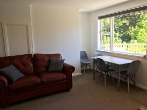 ein Wohnzimmer mit einem Sofa, einem Tisch und einem Fenster in der Unterkunft Sycamore Villa, 2 bedroom apartment in Dunedin