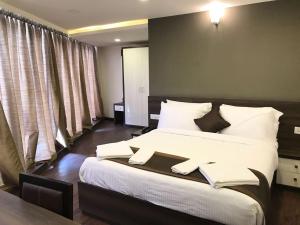 a bedroom with a large bed with white sheets and pillows at Hotel Royal Inn - Electronic City in Bangalore