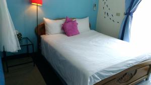 uma pequena cama com almofadas roxas num quarto em Breadtree Homestay em Wujie