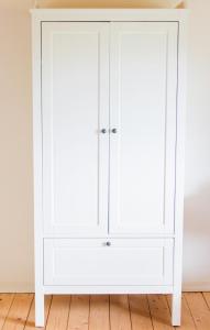 einen weißen Kleiderschrank mit zwei Türen in einem Zimmer in der Unterkunft Wilhelmshof Feggendorf in Feggendorf