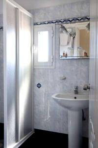 a white bathroom with a sink and a shower at Klonos Anna in Egina