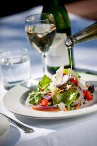 einen weißen Teller mit Salat und ein Glas Wein in der Unterkunft Fugitives Drift Guest House in Rorkeʼs Drift