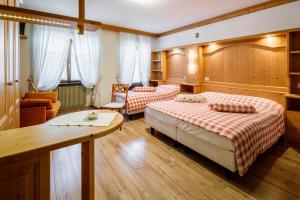 ein Hotelzimmer mit zwei Betten und einem Tisch in der Unterkunft Hotel Posta in Sappada