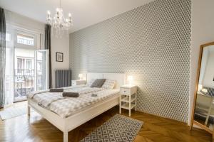 ブダペストにあるMegszűnt - Charming Design Apartment with balconyの白い大型ベッドと壁が備わるベッドルーム1室が備わります。