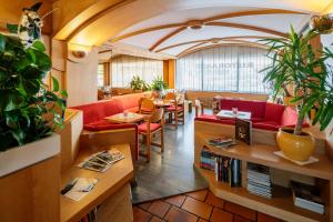 un restaurante con sofás rojos, mesa y sillas en Hotel Posta, en Sappada
