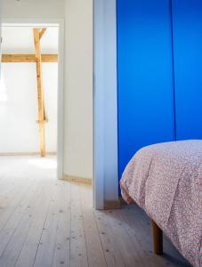um quarto com uma cama com uma parede azul e um piso de madeira em De Vakantieschuur em Sint-Laureins