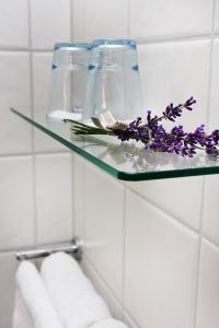 una estantería de cristal en un baño con flores púrpuras. en Sahlströmsgården en Torsby