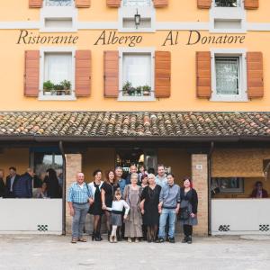 un gruppo di persone che si trovano di fronte a un edificio di Ristorante Albergo Al Donatore a Teòr