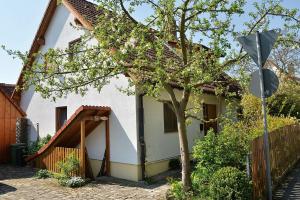 Una casa blanca con un árbol delante. en Ferienwohnung am Bimbach, en Herzogenaurach