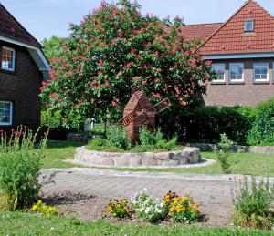 un jardín con una estatua delante de un árbol con flores en Ferienwohnungen zum Neuensiener See P, en Lancken-Granitz