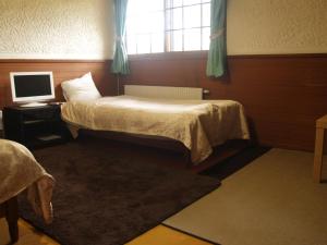 a bedroom with a bed and a computer on a table at Woody House Kazamidori in Myoko