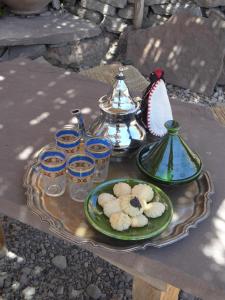 een tafel met een bord koekjes en een theeset bij Gite Tigmi Azrur in Tabant