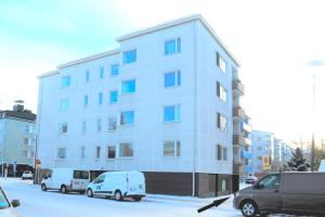 Ein weißes Gebäude mit zwei Vans davor. in der Unterkunft Apartment City-Pekka in Rovaniemi