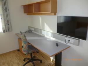 a kitchen with a desk with a television and a chair at Kolpinghaus Spittal in Spittal an der Drau