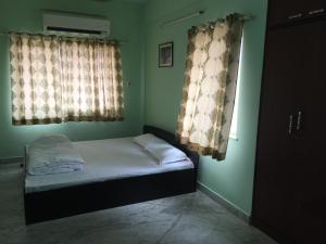 Nalanda Tulip في كولْكاتا: غرفة نوم صغيرة بها سرير ونوافذ