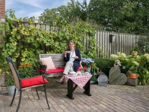 a woman sitting on a bench in front of a garden at B&B Het Pronkbed in Oirschot