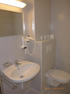 a white bathroom with a sink and a toilet at Kolpinghaus Spittal in Spittal an der Drau