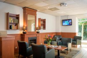 een wachtkamer met een tafel en stoelen en een open haard bij Campanile Hotel & Restaurant Breda in Breda