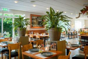 a restaurant with tables and chairs and potted plants at Campanile Hotel & Restaurant Breda in Breda