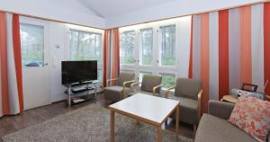 sala de estar con TV, sillas y ventanas en Holiday Club Kalajoki Cottages, en Kalajoki