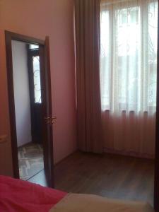 1 dormitorio con 1 cama y una ventana con cortinas en Vita, en Tiflis
