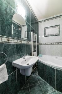 uma casa de banho com um lavatório, uma banheira e um espelho. em Valašský Hotel a Pivní lázně OGAR em Luhačovice