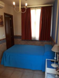 a blue bed in a room with a window at Pension Doña Trinidad in Seville