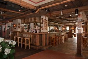 Gästehaus Dorf-Alm في فيلنغن: وجود بار في مطعم بسقوف خشبية وباصات خشبية
